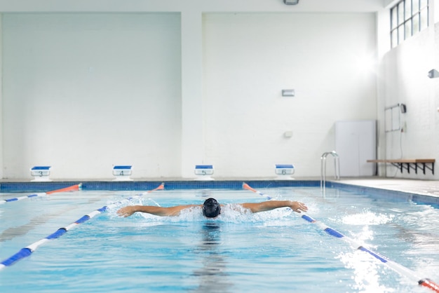 Foto biraciale jonge vrouwelijke zwemmer traint binnen in een zwembad kopie ruimte