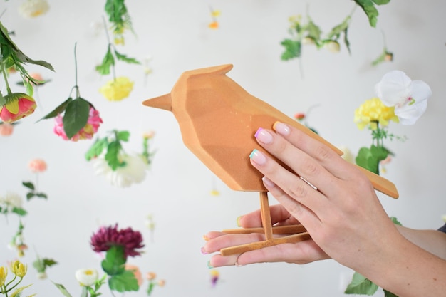 Bird for decoration in the hands of a young girl on a floral background