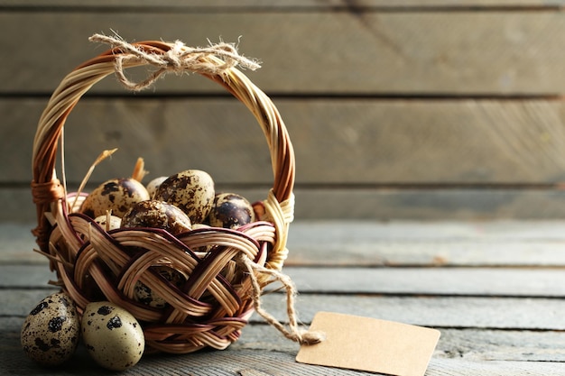 Bird eggs in wicker basket on wooden background