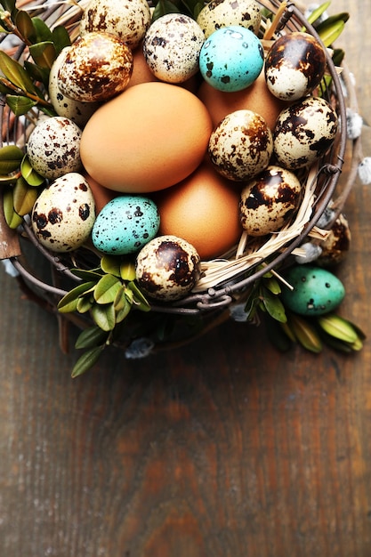 Bird eggs in wicker basket on wooden background