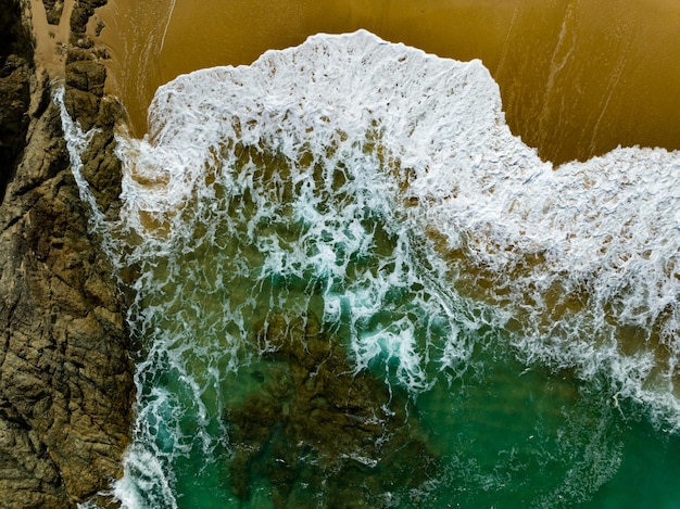 Photo bird eye view seashore with big wave crashing on rock cliff beautiful waves sea surface in sunny day summer background amazing seascape top view seacoast landscape view