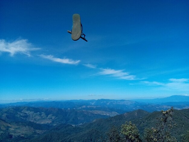 Bird flying over mountains against blue sky