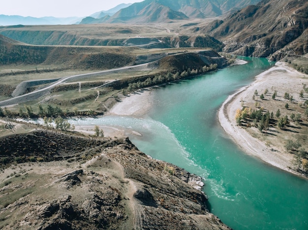 Bird view on a long light turquoise river stretching along the sandy banks, dividing into two directions at the end of the river