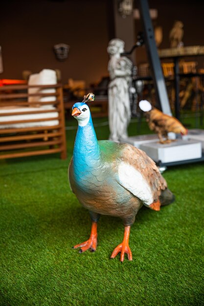 A bird with a bug on its head stands on a fake grass area.