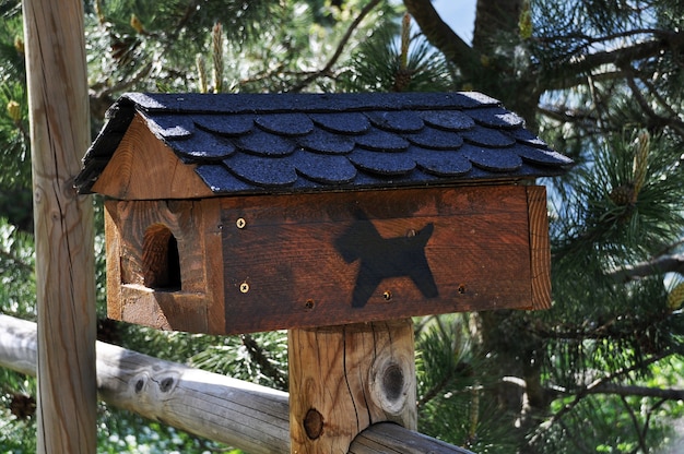 Birdhouse for birds in the shape of a doghouse on a wooden fence