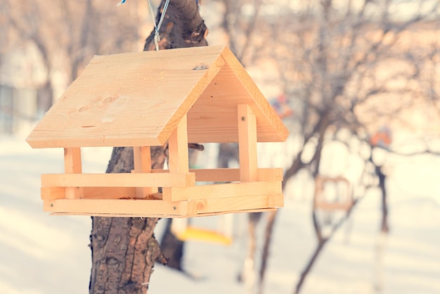 Birdhouse hanging on the tree against the background of the fence and snow Toned