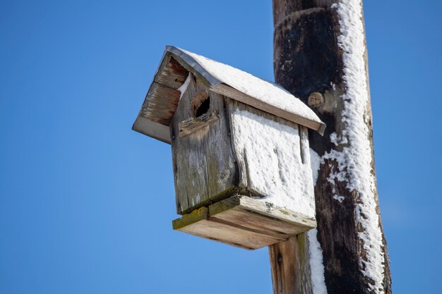 Birdhouse hangs on a pillar covered with snow. High quality photo