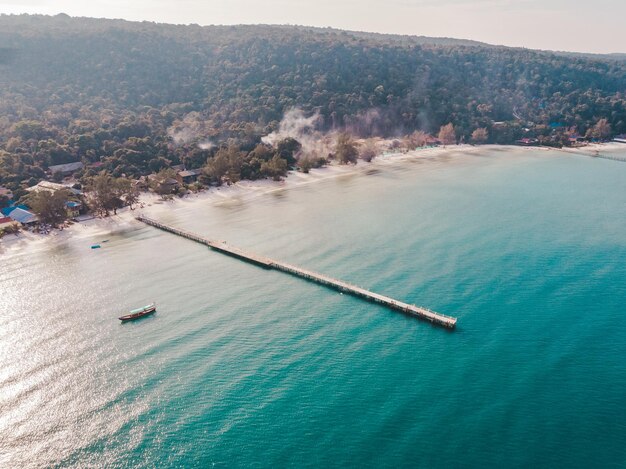 Birds eye drone aerial view of single pier in crystal clear blue sea on secluded beach on Cambodian island Koh Rong on sunny summer