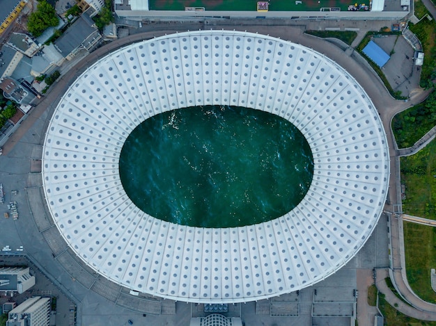 屋根の中に海のターコイズブルーの水があるサッカースタジアムのドローンからの鳥の目のパノラマビュー。上面図。