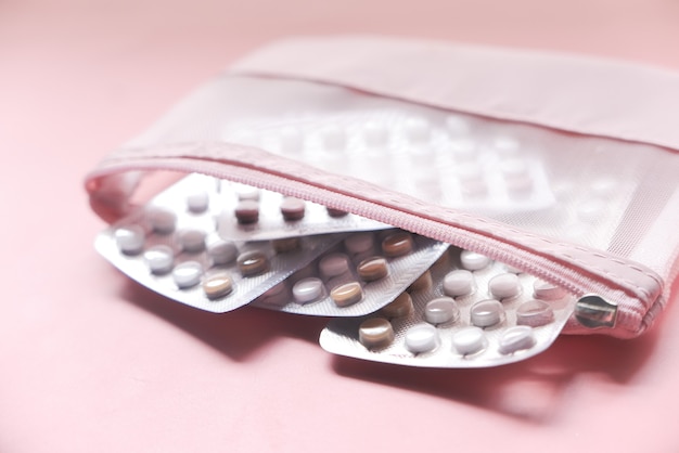 Photo birth control pills on pink surface, close up .