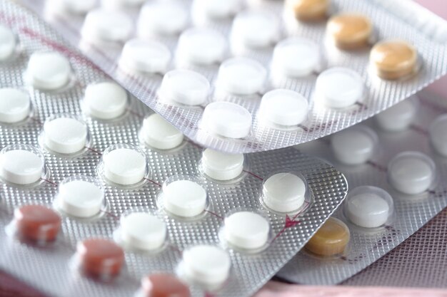 Birth control pills on wooden background close up