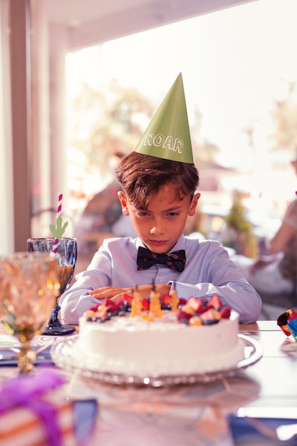 Birthday boy feeling sad and looking at the birthday cake