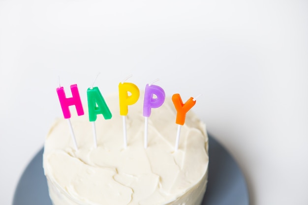 Torta di compleanno, su un pan di spagna cremoso l'iscrizione felicità. il concetto di sorpresa per le vacanze e il compleanno.