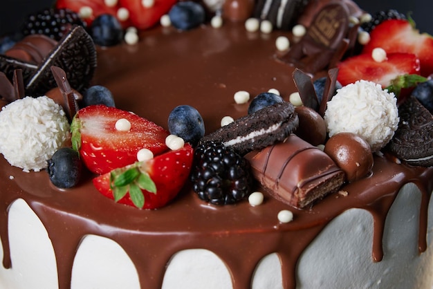 Birthday cake on dark background close up of cake decorated with fresh berries and chocolate sweets