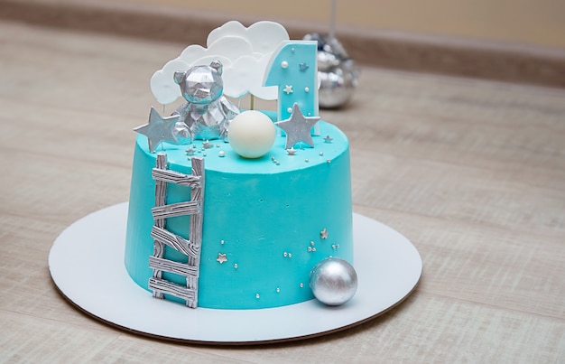 Birthday cake for a litltle boy with light blue mirror glaze. Chocolate decor and number one.