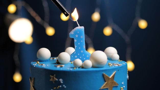 Birthday cake number 1 stars sky and moon concept, blue candle is fire by lighter. Copy space on right side of screen. Close-up