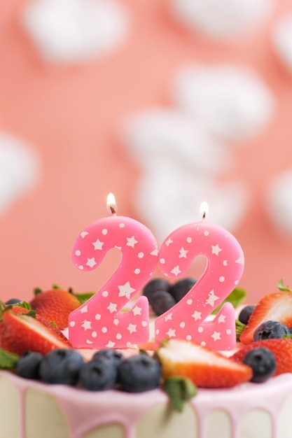 생일 케이크 번호 22 흰 구름이 있는 분홍색 배경에 케이크에 있는 아름다운 분홍색 촛불 근접 촬영 및 수직 보기