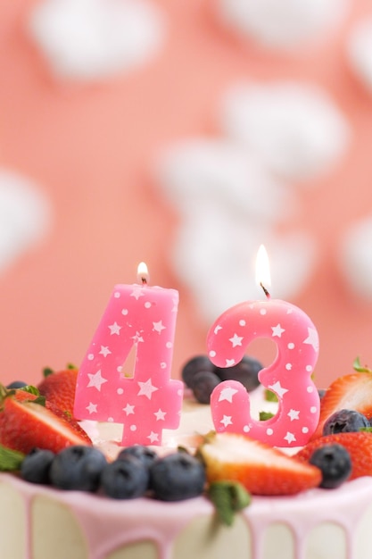 Foto torta di compleanno numero 43 bella candela rosa in torta su sfondo rosa con nuvole bianche vista in primo piano e verticale