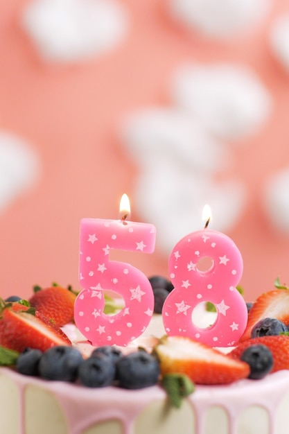 Birthday cake number 58 Beautiful pink candle in cake on pink background with white clouds Closeup and vertical view