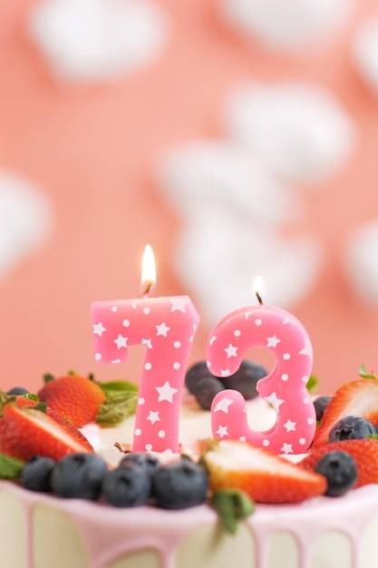 생일 케이크 번호 73 흰 구름이 있는 분홍색 배경에 케이크에 있는 아름다운 분홍색 촛불 근접 촬영 및 수직 보기