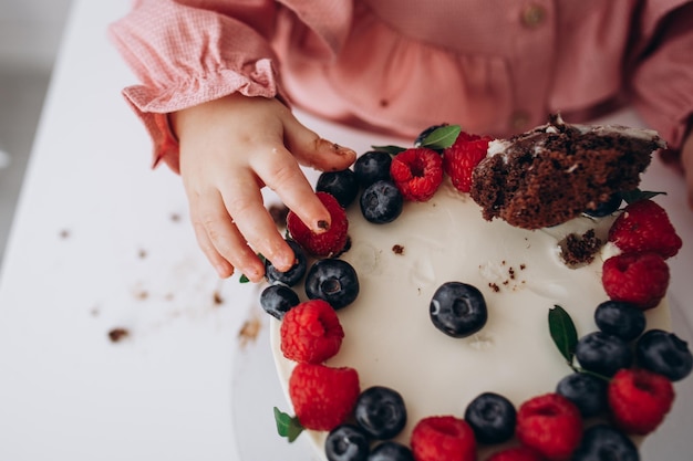 写真 ベリーラズベリーとブルーベリーの子供たちの手でバースデーケーキ