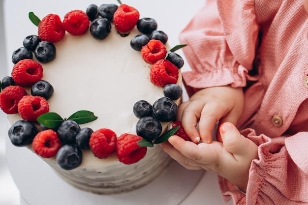 Foto torta di compleanno con bacche di lampone e mirtillomani per bambini