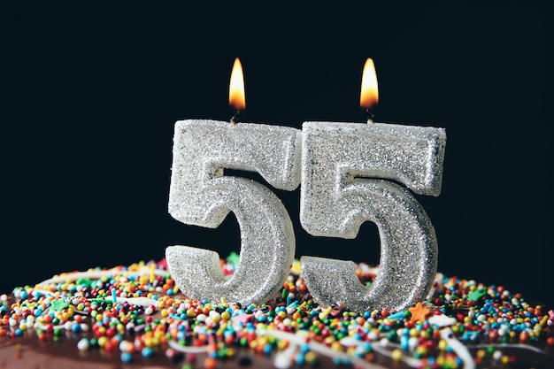 Birthday cake with burning candles on dark background