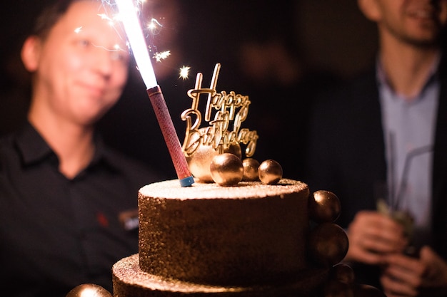 Birthday cake with candles, bright lights bokeh.