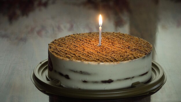 Photo birthday cake with colorful burning candle in dark birthday cake with candle for any birthday