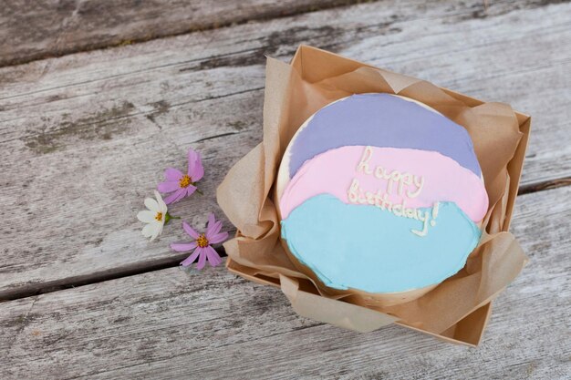 Birthday cake with flowers on retro wooden table pink tart in naked style with letters