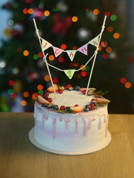 Foto torta di compleanno con frutta e luci sfocate