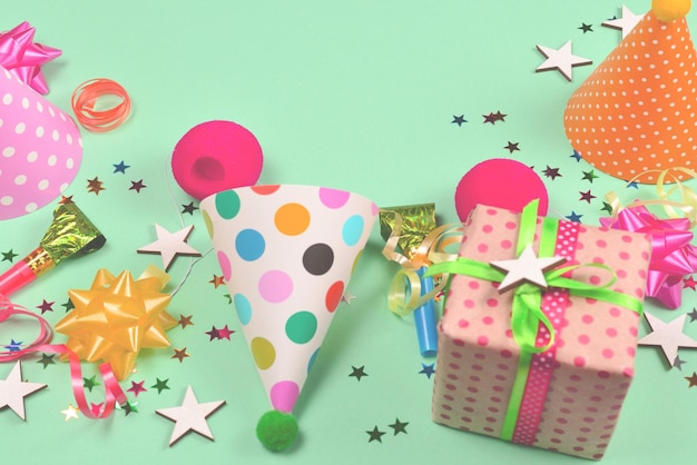 Birthday caps present confetti ribbons stars clown noses on a green background Space for text or design