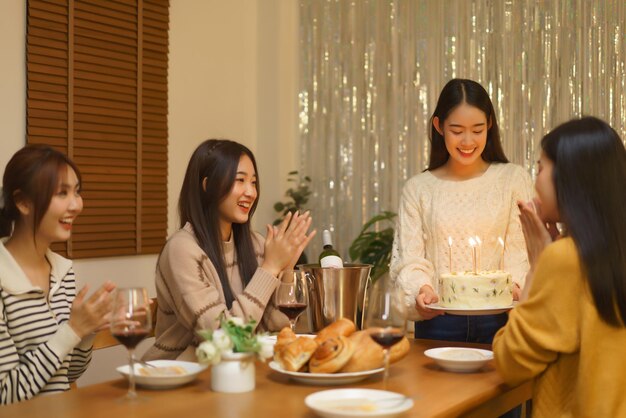 생일 축하 개념 파티에서 친구를 놀라게 하기 위해 생일 케이크를 들고 있는 아시아 소녀들