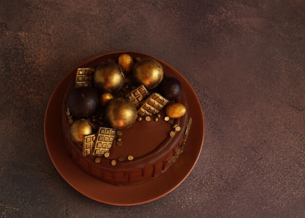 Birthday chocolate cake with golden balls on beige background