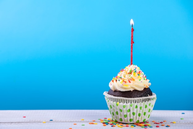 Birthday cupcake on blue with multicolor candles.