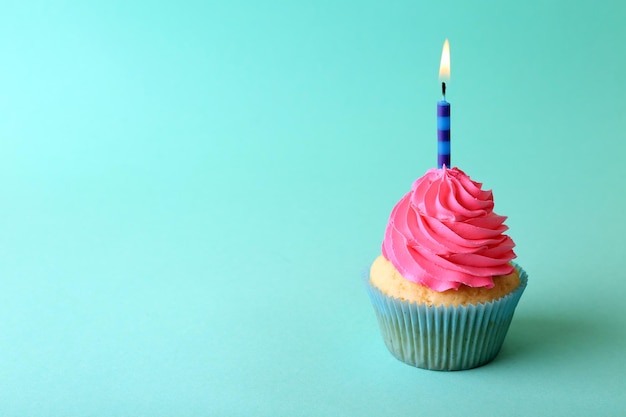 Birthday cupcake with candle on turquoise background