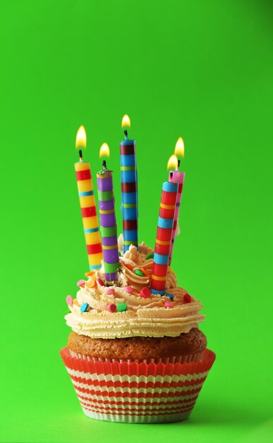 Birthday cupcake with candles on color background