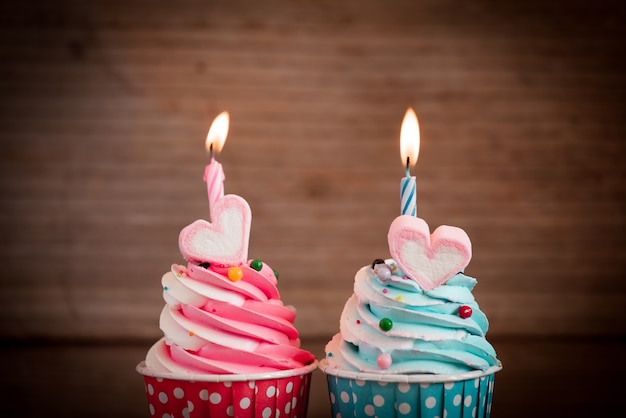 birthday cupcake with sweet heart shape of marshmallow and candle on wooden background