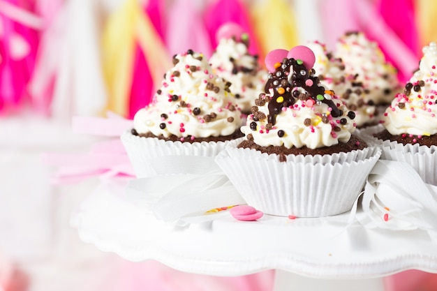 Birthday cupcakes with cheese cream and cake with multicolored decorations