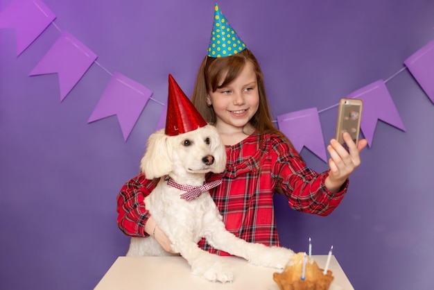 犬と子供の誕生日お祭りの帽子をかぶった犬がペットと一緒に自分撮りをするパーティー