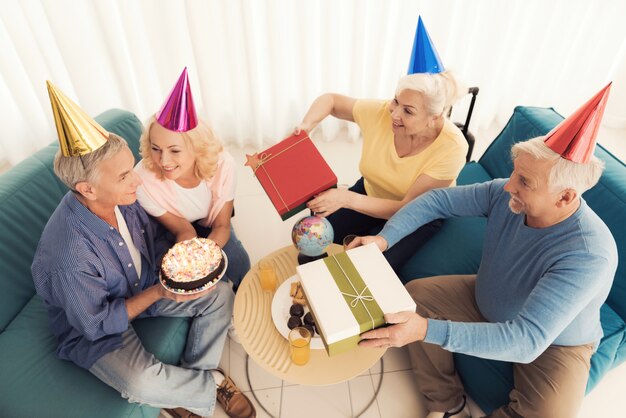 Birthday of the elderly person. People in a birthday hats.