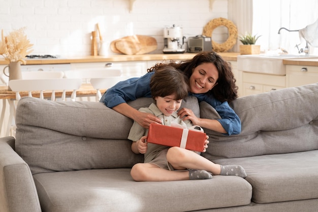 Regalo di compleanno per la mamma che si prende cura dei bambini che saluta il bambino con la scatola regalo per l'evento festivo