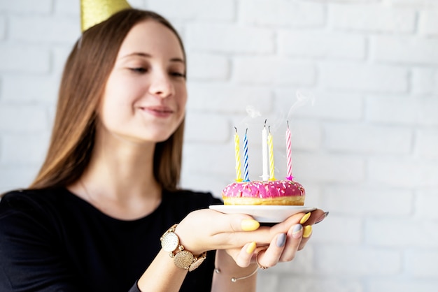 ドーナツにキャンドルを吹く誕生日の女の子