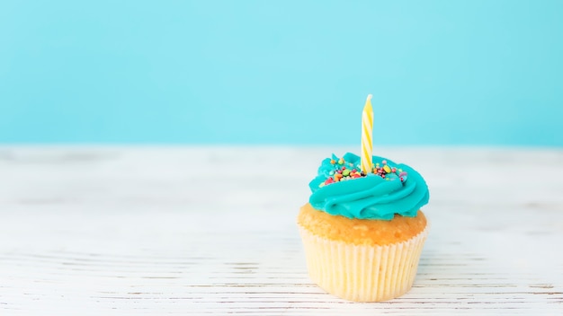 Concetto di auguri di compleanno. candela gialla su un muffin o un cupcake.