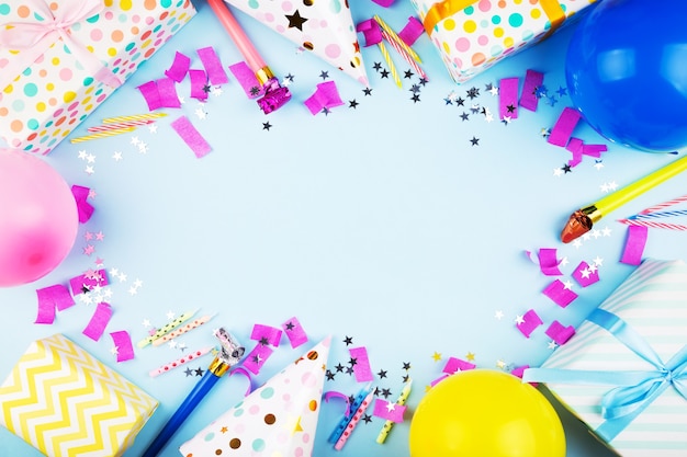 Birthday party attributes. Colorful balls, confetti, gifts, candles for cake. Blue background. Top view. Copy space