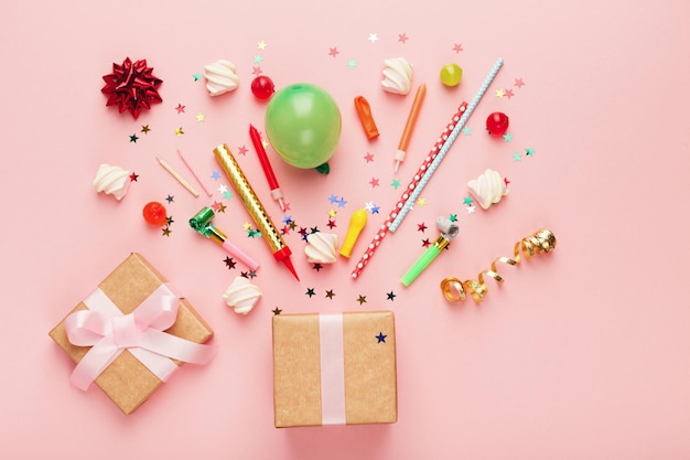 Birthday party background with gifts and firework of confetti, sweets, balloon on pink backdrop, copy space, top view.