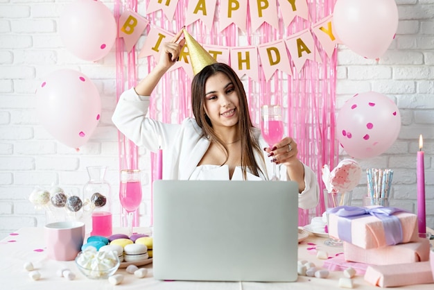Birthday party Birthday tables Attractive brunette woman in white party clothes celebrating birthday using video call chatting with friends