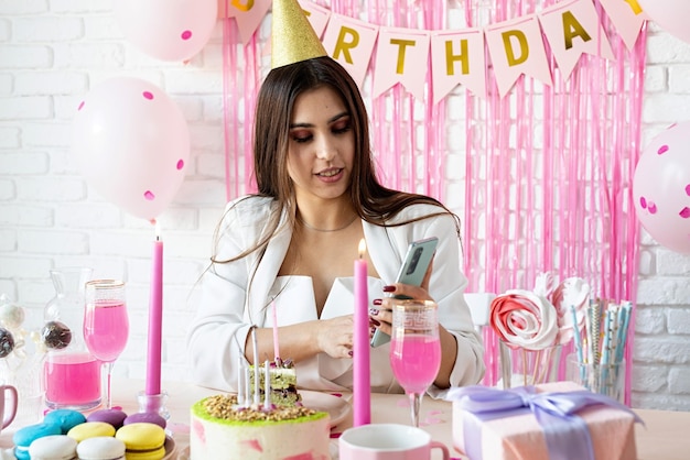 Birthday party Birthday tables Attractive woman in white party clothes celebrating birthday taking selfie on mobile