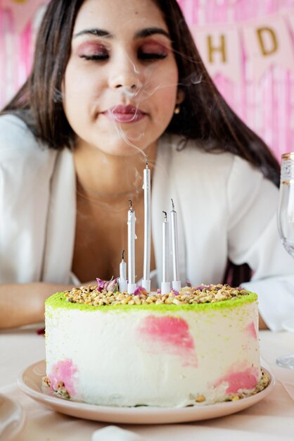 Birthday party Birthday tables Attractive woman in white party clothes preparing birthday table with cakes cakepops macarons and other sweets making wish