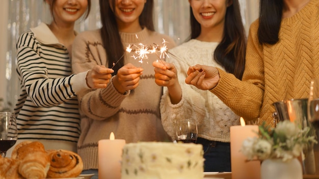 誕生日パーティーのコンセプト アジアの女の子が誕生日パーティーで夕食を祝いながら線香花火を演奏